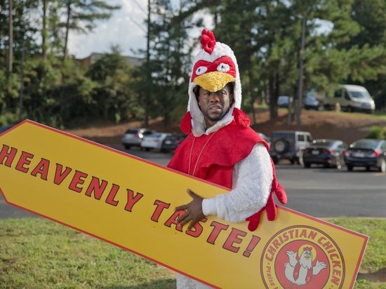 Een man in een kippenkostuum met een gele pijl met 'CHRISTIAN CHICKEN' erop.