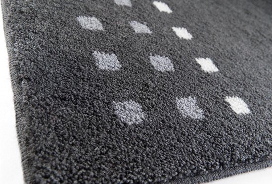 Close-up van donkergrijze badmat met witte en lichtgrijze vierkantjes.
