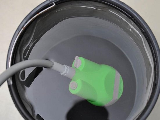 Groene draagbare douchepomp met slang in een donkere emmer met water.