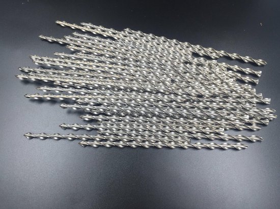 Veel losse, spiraalvormige metalen ankers liggend op een zwarte ondergrond.
