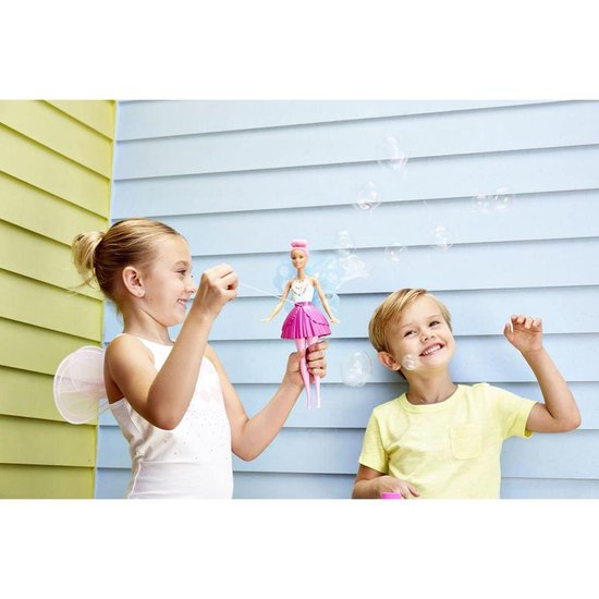 Twee kinderen met Barbie Dreamtopia zeemeerminpop in de tuin. Meisje blaast bubbels, jongen kijkt blij.