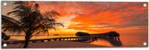 Tuinposter – Zonsondergang op het Strand met Palmbomen en Paalwoningen - 90x30 cm Foto op Tuinposter (wanddecoratie voor buiten en binnen)