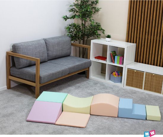 Blocs de jeu souples aux couleurs pastel, disposés en parcours avec un départ plat, une rampe, un pont, des marches et un arc.