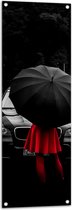 WallClassics - Tuinposter – Vrouw in Rood bij Zwarte Auto met Paraplu - 40x120 cm Foto op Tuinposter (wanddecoratie voor buiten en binnen)