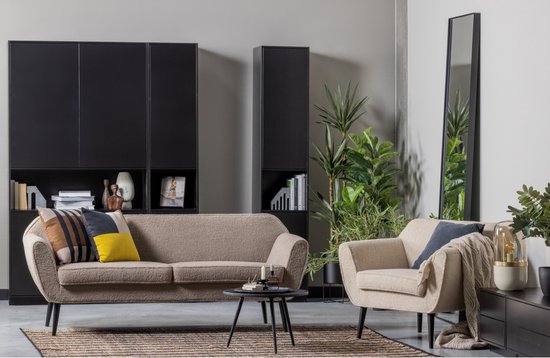 Woonkamer met een beige bank, beige fauteuil, zwarte salontafel en spiegel.