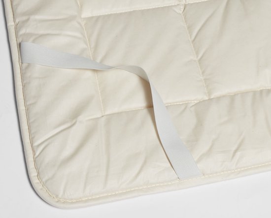 Detail van crème kleurige wollen onderdeken met elastische hoekband.