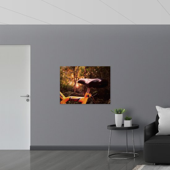 WallClassics - Poster Glanzend – Zadel van Gele Fiets in het Bos - 100x75 cm Foto op Posterpapier met Glanzende Afwerking