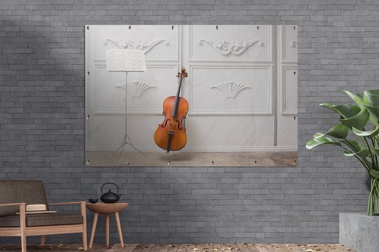 Tuinposter 180x120 cm - Tuindecoratie Een cello tegen een witte muur - Poster voor in de tuin - Buiten decoratie - Schutting tuinschilderij - Tuindoek muurdecoratie - Wanddecoratie balkondoek