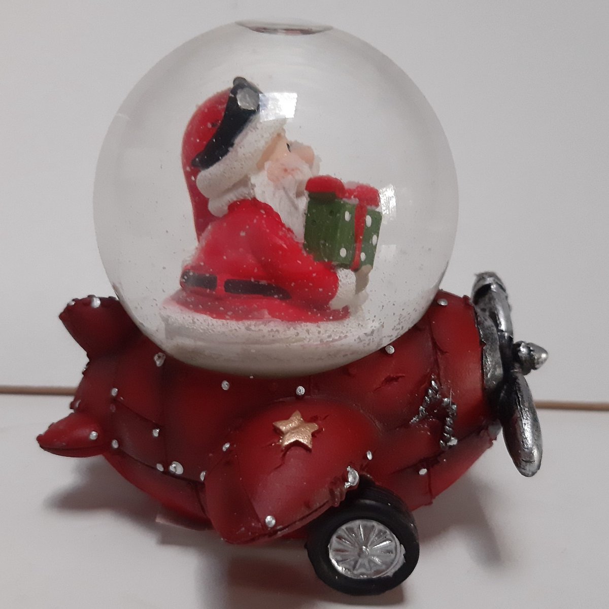 Sneeuwbol kerstman in rood vliegtuig met groen cadeau 10 cm hoog - G. Wurm