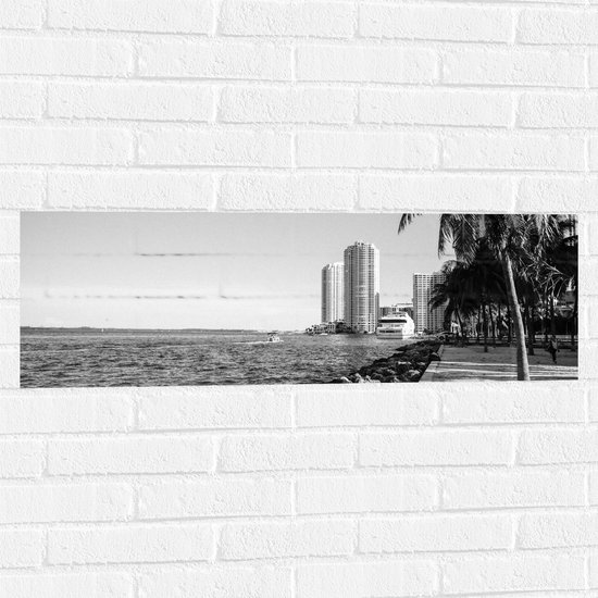 Muursticker - Palmbomen op het Strand met Uitzicht op Hoge Gebouwen Zwart/Wit - 90x30 cm Foto op Muursticker