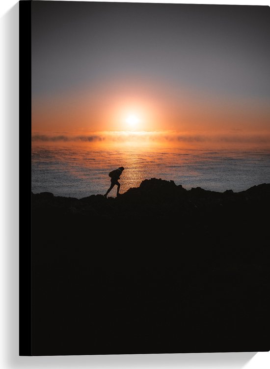 WallClassics - Canvas - Man lopend over Berg aan de Zee met Zonsondergang - 40x60 cm Foto op Canvas Schilderij (Wanddecoratie op Canvas)