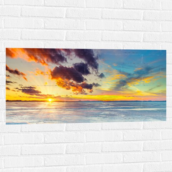 WallClassics - Muursticker - Zonnestralen door Meerkleurige Lucht boven het Water - 100x50 cm Foto op Muursticker