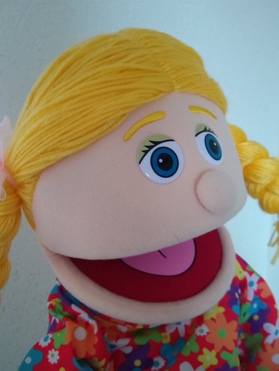 Close-up van buiksprekpop Cindy's gezicht, met blonde vlechten en blauwe ogen.