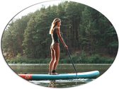 Dibond Ovaal - Blonde Vrouw op Supbord op Water langs Rij Bomen - 80x60 cm Foto op Ovaal (Met Ophangsysteem)
