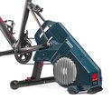 Elite fietstrainer met direct drive, blauwe behuizing met zilveren koelvinnen en een racefiets gemonteerd.