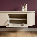 Zandkleurig houten tv-meubel met een open vak en twee decoratieve herten, op een paarse muur.