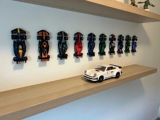 Dix voitures de F1 LEGO exposées sur une étagère. Une Porsche LEGO blanche est sur l'étagère inférieure.