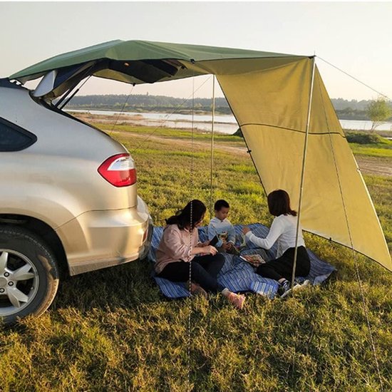 Twee vrouwen en een kind picknicken onder een beige autoluifel, bevestigd aan de open achterklep.