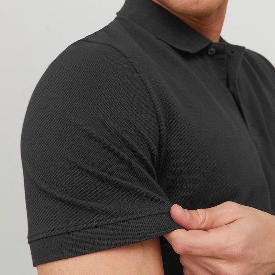 Close-up van de mouw van een donkergrijze polo met korte mouwen, gedragen door een man.
