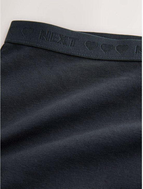 Detail van de donkerblauwe elastische band met 'NEXT' en hartjesprint op een boxer.