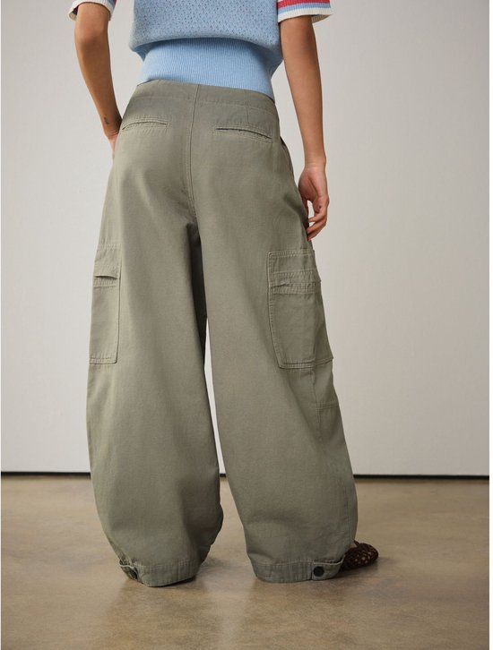 Achterkant van een model in een wijde olijfgroene cargo broek, met opgestikte zakken.