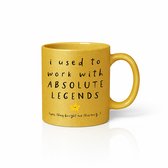 Gouden mok met de tekst 'i used to work with ABSOLUTE LEGENDS (yes, they bought me this mug)' en een gele ster.