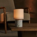 Tafellamp met marmeren voet en linnen kap, op een houten salontafel.