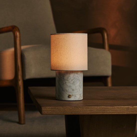 Tafellamp met marmeren voet en linnen kap, op een houten salontafel.