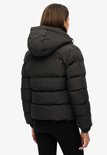 Zicht op de achterkant van een zwarte Superdry pufferjas met capuchon.