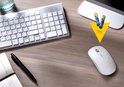 Zilverkleurig toetsenbord, witte muis, pen en notitieblok op een houten bureau met twee AAA Varta batterijen.