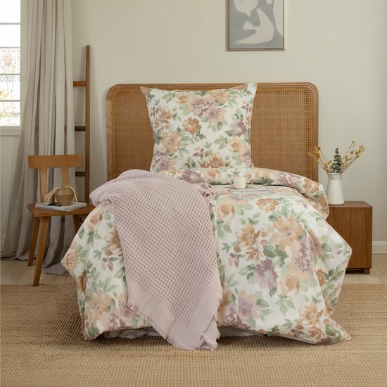 Een bloemenprint dekbedovertrek met bloemen in groen, paars, oranje en roze op een witte achtergrond.