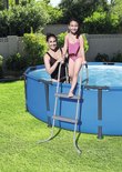 Vrouw en meisje in badkleding bij een ronde blauwe zwembad met een grijze ladder.