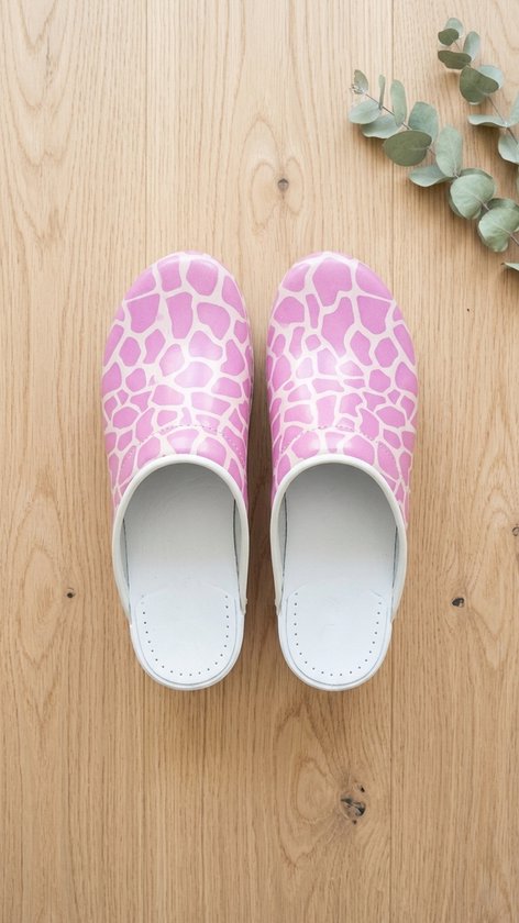Roze klompen met wit giraffeprint op een houten achtergrond.