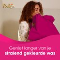 Femme aux cheveux bouclés enfouissant son visage dans un coussin rose vif. Texte : Profitez plus longtemps de votre linge aux couleurs éclatantes.