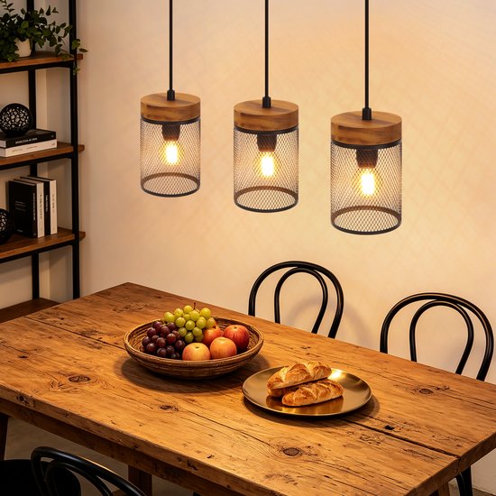 Driepers hanglamp met houten details boven een houten tafel met fruit en brood.