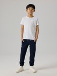 Jongens in een witte t-shirt en donkerblauwe joggingbroek.