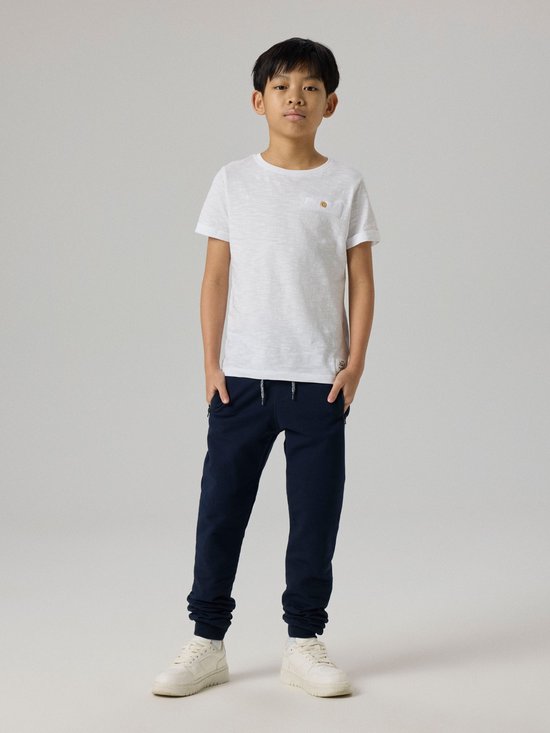 Jongens in een witte t-shirt en donkerblauwe joggingbroek.