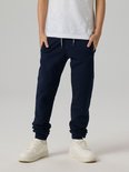 Jongen in donkerblauwe joggingbroek met trekkoord en ritszakken.