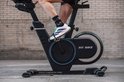 Zwarte Fit Bike Race Magnetic Pro spinfiets met blauwe accenten op het vliegwiel, van dichtbij gezien tijdens gebruik.