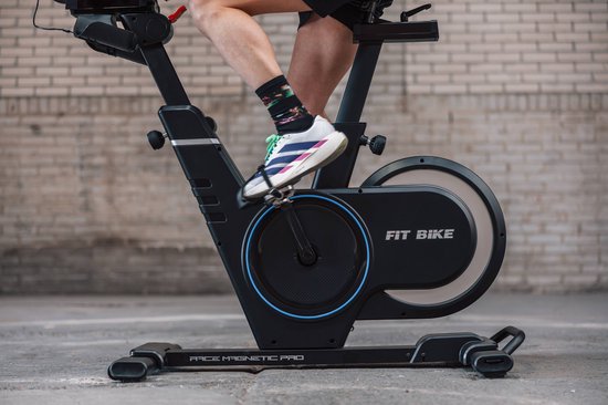 Zwarte Fit Bike Race Magnetic Pro spinfiets met blauwe accenten op het vliegwiel, van dichtbij gezien tijdens gebruik.