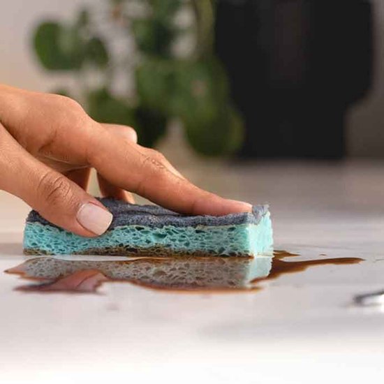 Une éponge à récurer bleue est utilisée pour nettoyer une table.