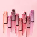 Assortiment Burt's Bees getinte lippenbalsems in verschillende kleuren en tubes, met strepen van bijpassende kleuren erachter.