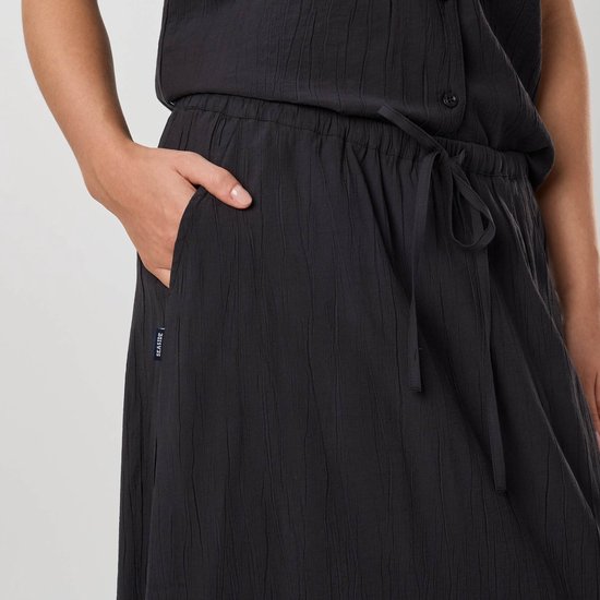 Detail van zwarte crinkle rok met rijgsluiting en label 'Seaside'.