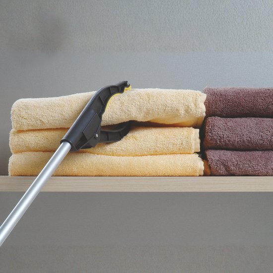 Grijparm met zwarte klem pakt een stapel beige en bruine handdoeken op een plank.