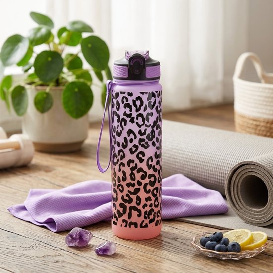 Paars-roze waterfles met luipaardprint op een houten tafel naast een yogamat en paarse handdoek.