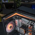 Gaming pc met oranje verlichting. Links een ventilator, rechts de moederbord met MSI koeler. Glazen zijkant.