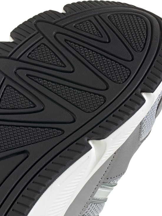 Detail van zwarte rubberen buitenzool met visgraatmotief van grijze Adidas sneaker.