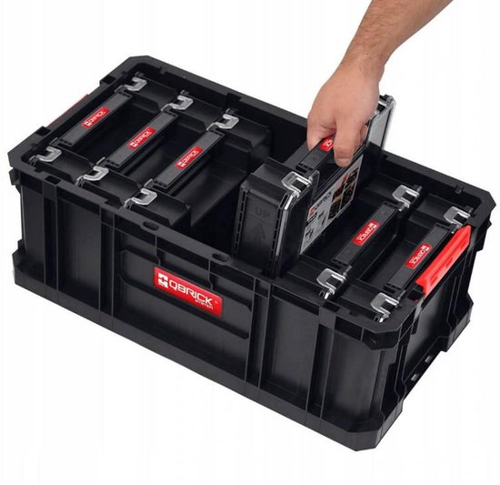 Zwarte Qbrick gereedschapskist met rode handgrepen en een hand die een organizer verwijdert.