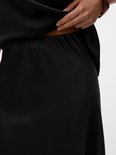 Femme portant une jupe midi en satin noir, gros plan de la ceinture.