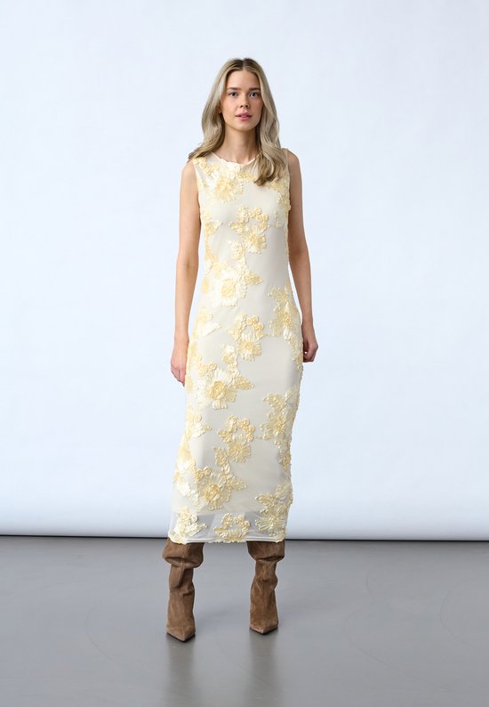 Mannequin portant une robe crème moulante sans manches, longueur mollet, avec applications florales.
